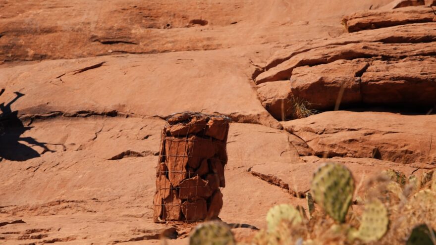 Wire mesh holds loose red rocks in place beside the Cathedral Rock Trail