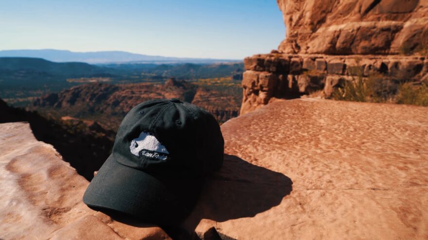 Black hat on a red rock ledge above Sedona’s Cathedral Rock view