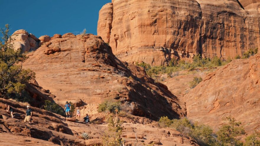 Hikers climb the red sandstone path on Cathedral Rock Trail in Sedona