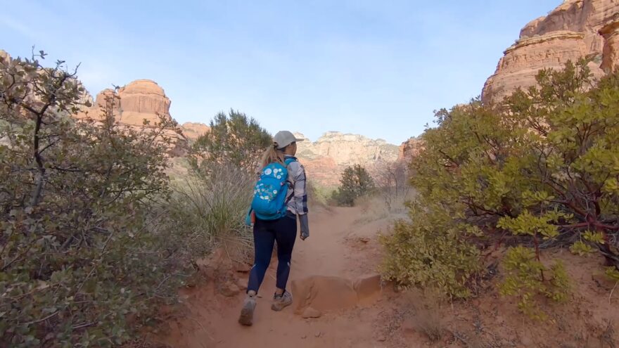 Hiker walks along Boynton Canyon Trail surrounded by red rock cliffs