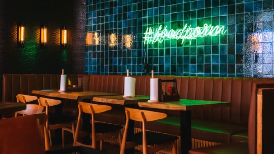 Restaurant booth seating sits below a green neon food sign in Sedona