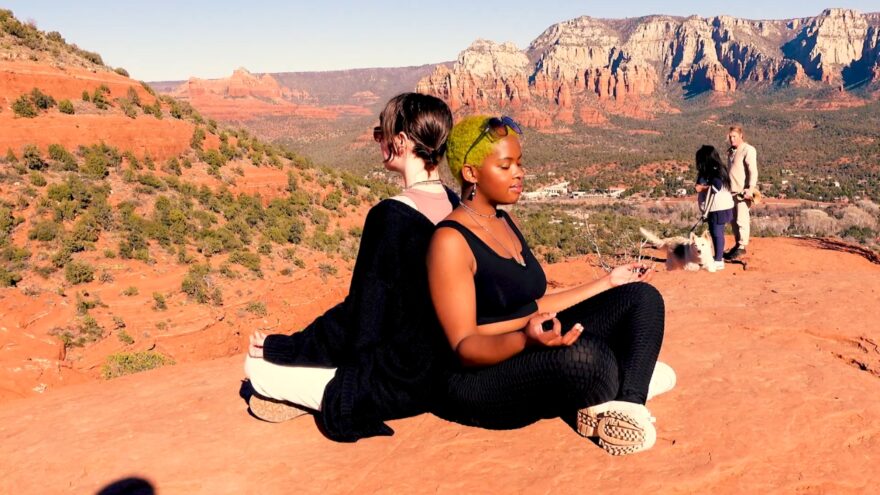 Two people meditating on red rocks at one of Sedona’s vortex sites