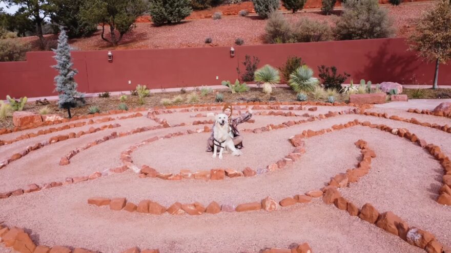 Person and dog sitting inside a red rock labyrinth garden in Sedona